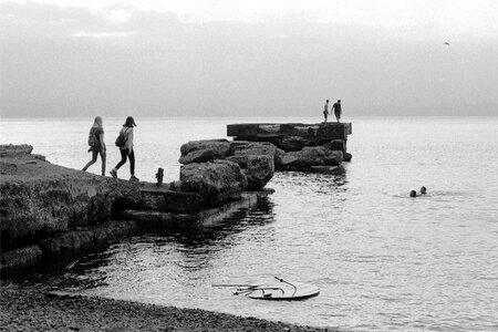 Black and white view of women walking together on rocky beach