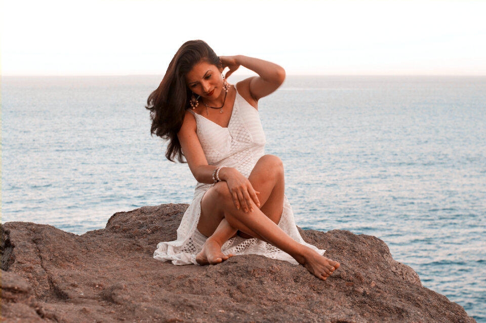 Sexy female sitting on the rock in the sea