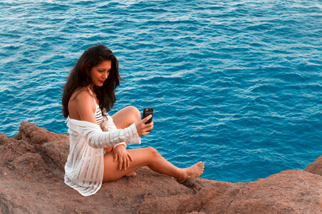 Sexy female sitting on the rock in the sea photo