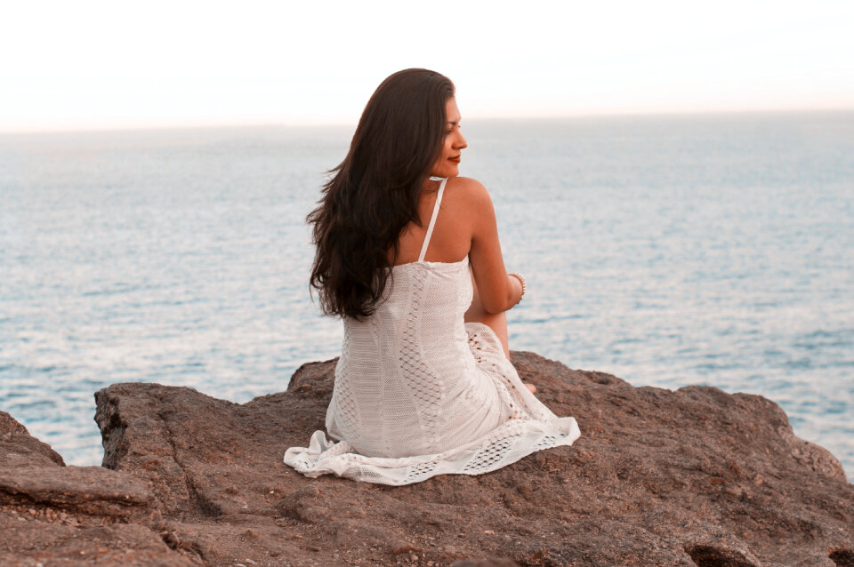 Sexy female sitting on the rock in the sea