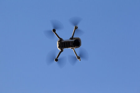 Drone hovering in a bright blue sky