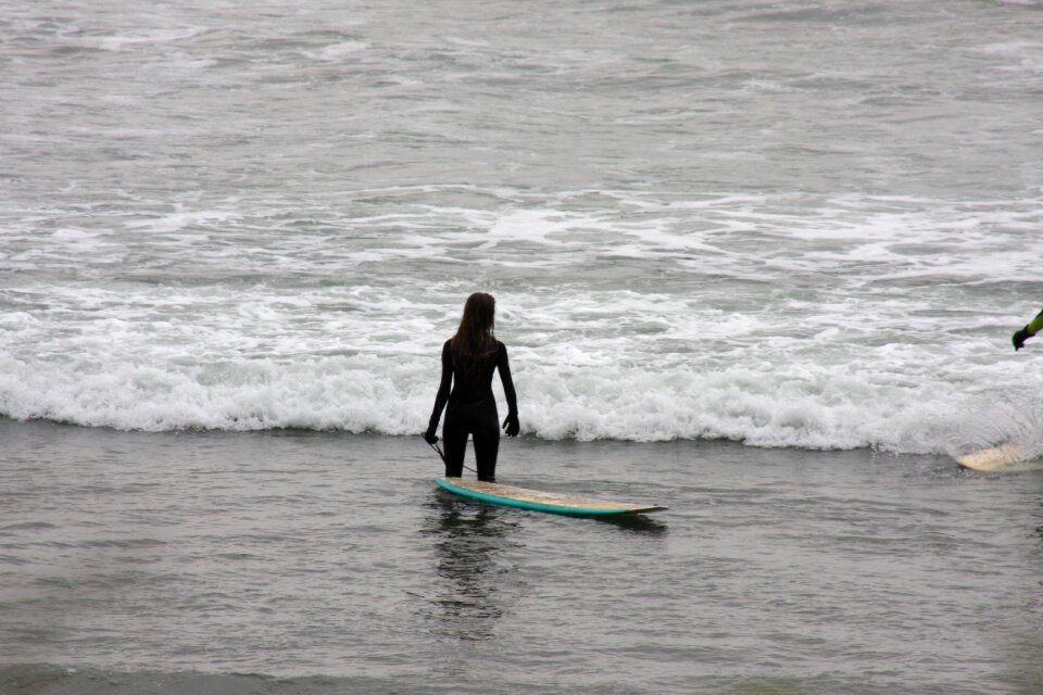 Lone Surfer carrying board along rugged Northern Oregon Coast