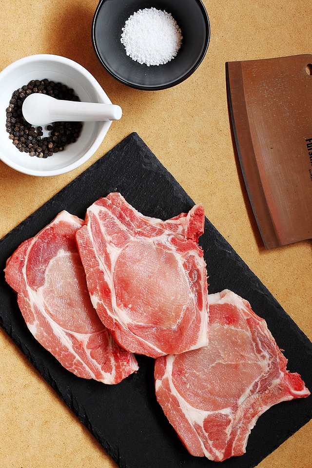 Prepping And Seasoning Raw Pork Chops With Slate And Cleaver