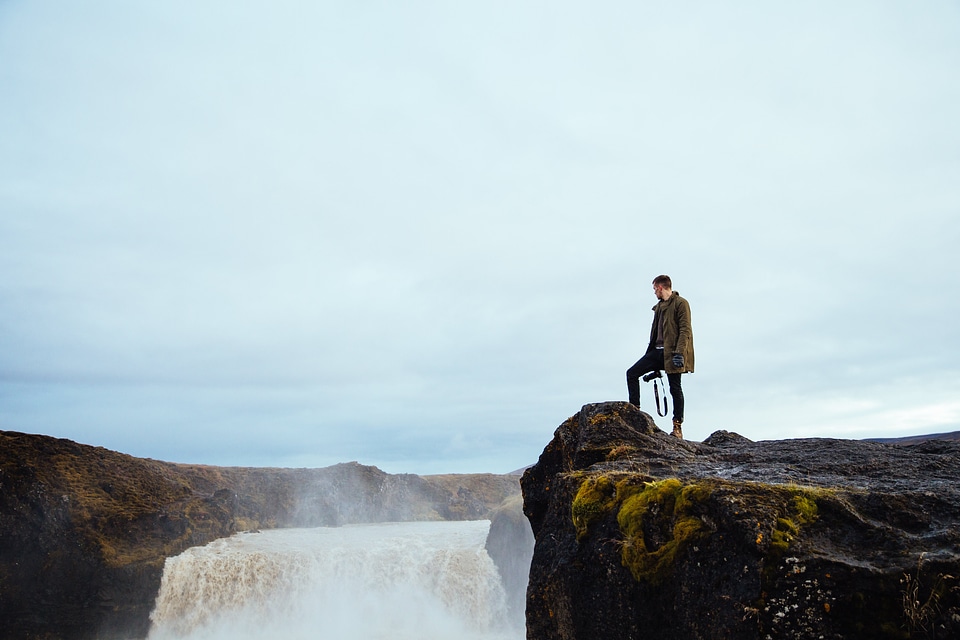 Hiker On Cliff By Waterfall photo