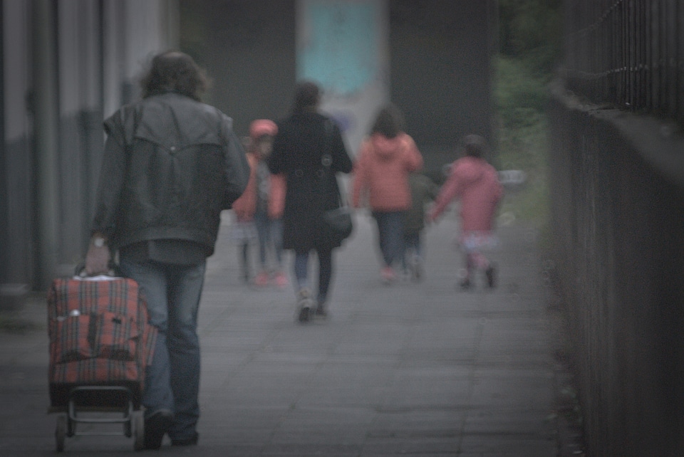 Man with shopper walking behind family
