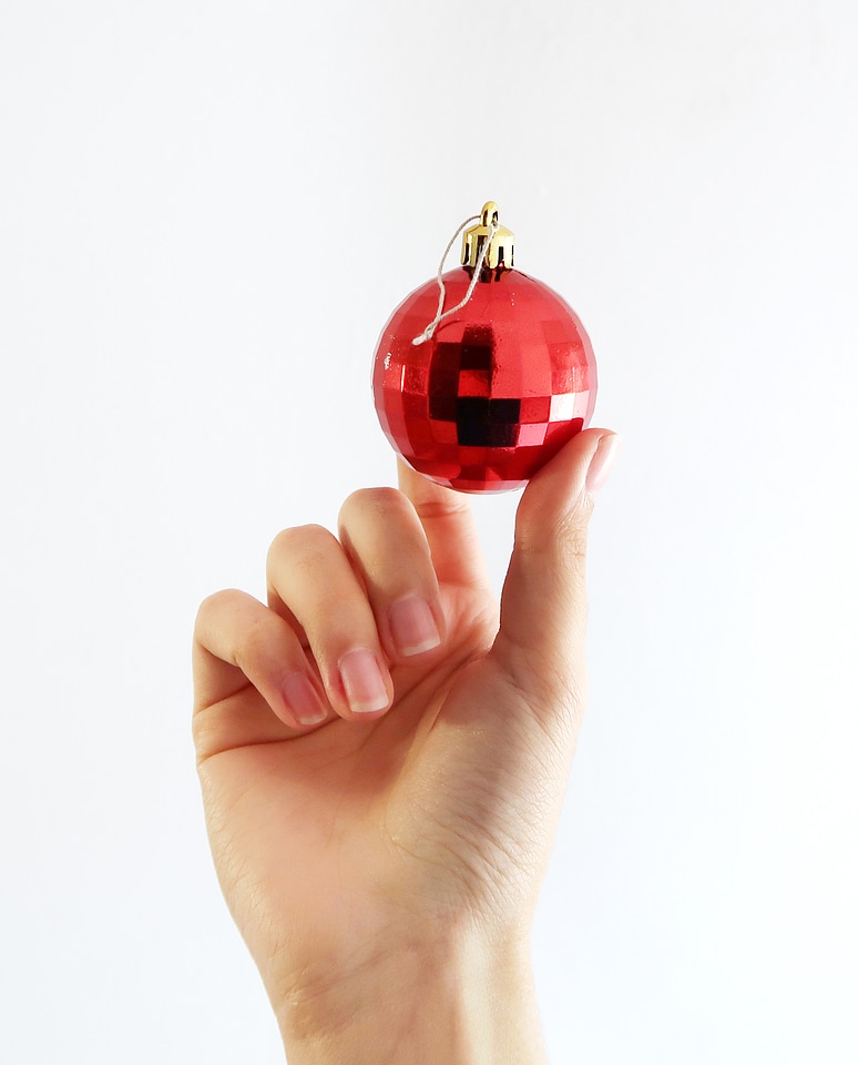 Hand Holding Red Christmas Ball on a White Background photo