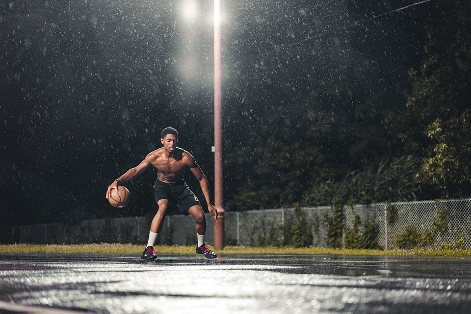Athlete Male Playing Basketball at Rainy Night Outdoors