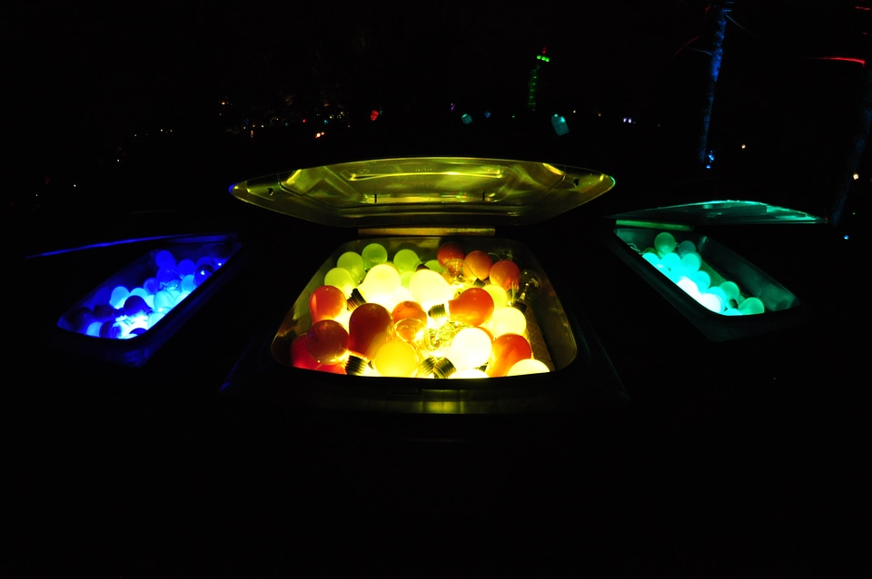 Three-colored glowing lightbulbs in trash cans