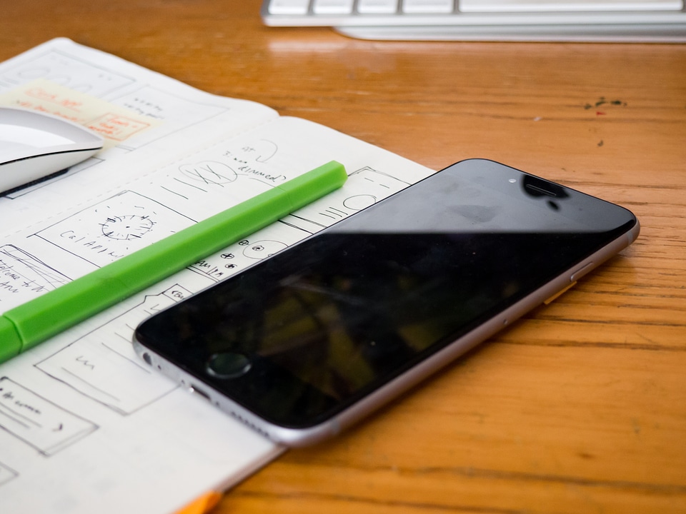 Phone and Sketchbook on Wooden Desk photo