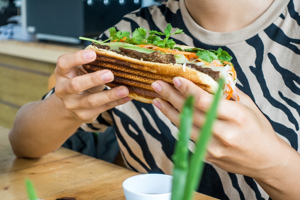 Girl eating fresh Vietnamese baguette banh mi
