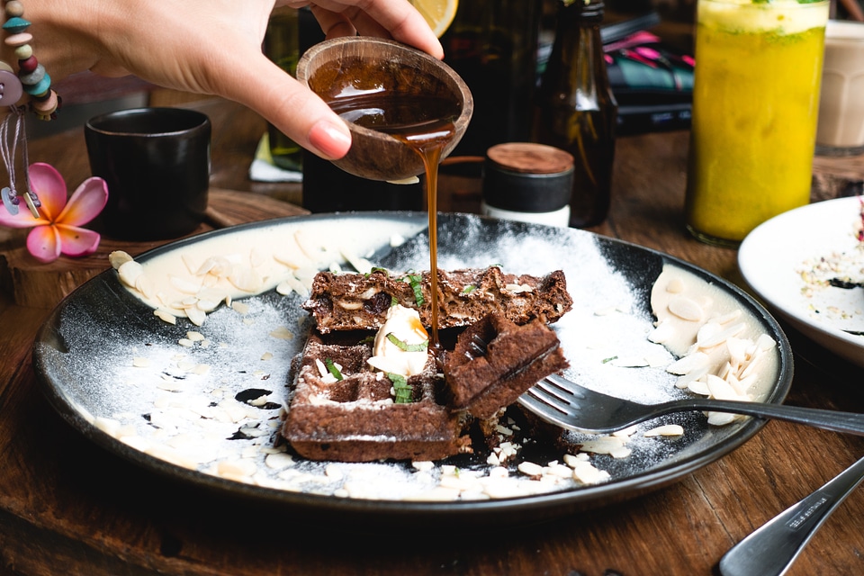 Pouring maple syrup on a chocolate waffle