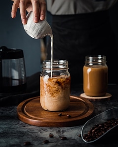 Pouring milk in a jar with coffee photo