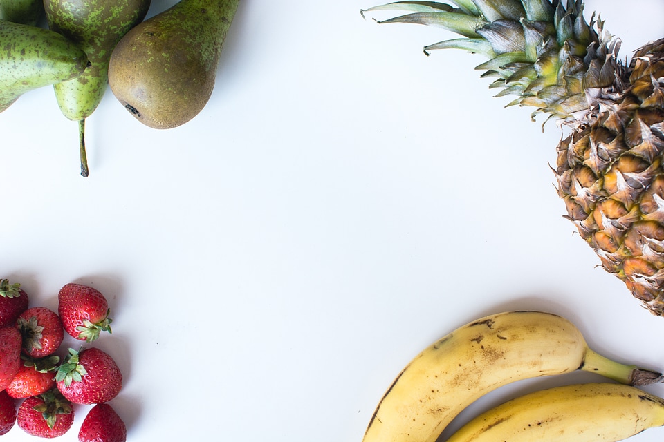 Aerial shot of fresh bananas, pears, strawberries and pineapple
