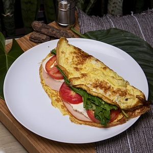 Homemade omelet with ham, cheese, spinach and tomatoes photo