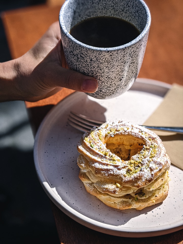 Girl having filtered coffee with puffed dessert