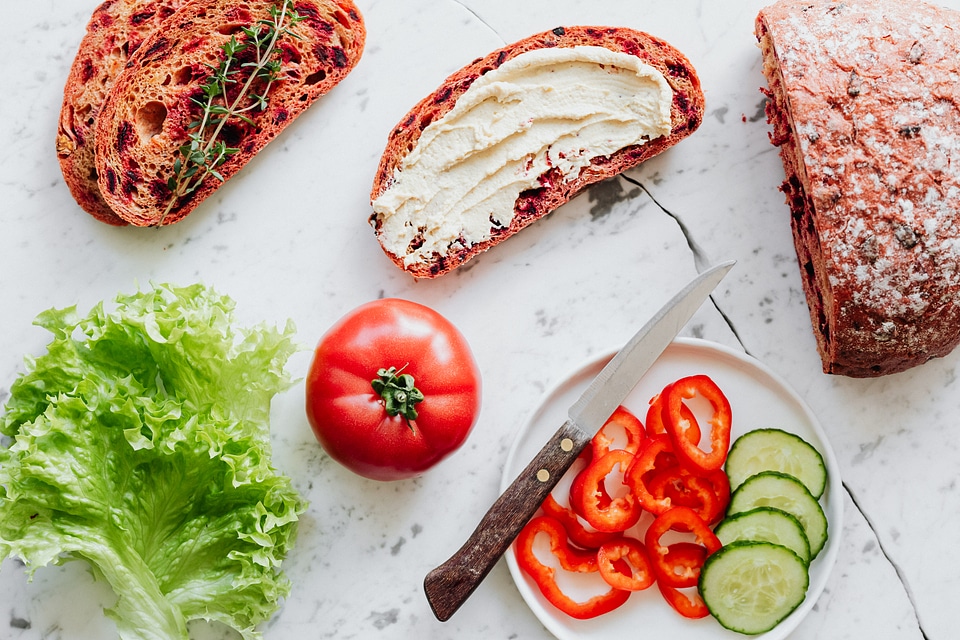 Preparing sandwich with hummus spread and fresh vegetables