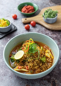 Chili noodle soup with fresh vegetables on top