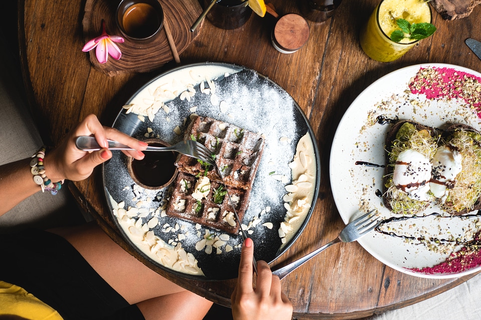 Girl eating chocolate waffle for breakfast in a tropical coffeeshop