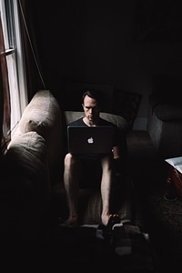 Man Working on his Laptop on the Sofa at Home photo