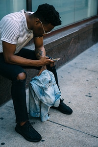 Man Holding his iPhone Wearing Black Ripped Knee Jeans photo