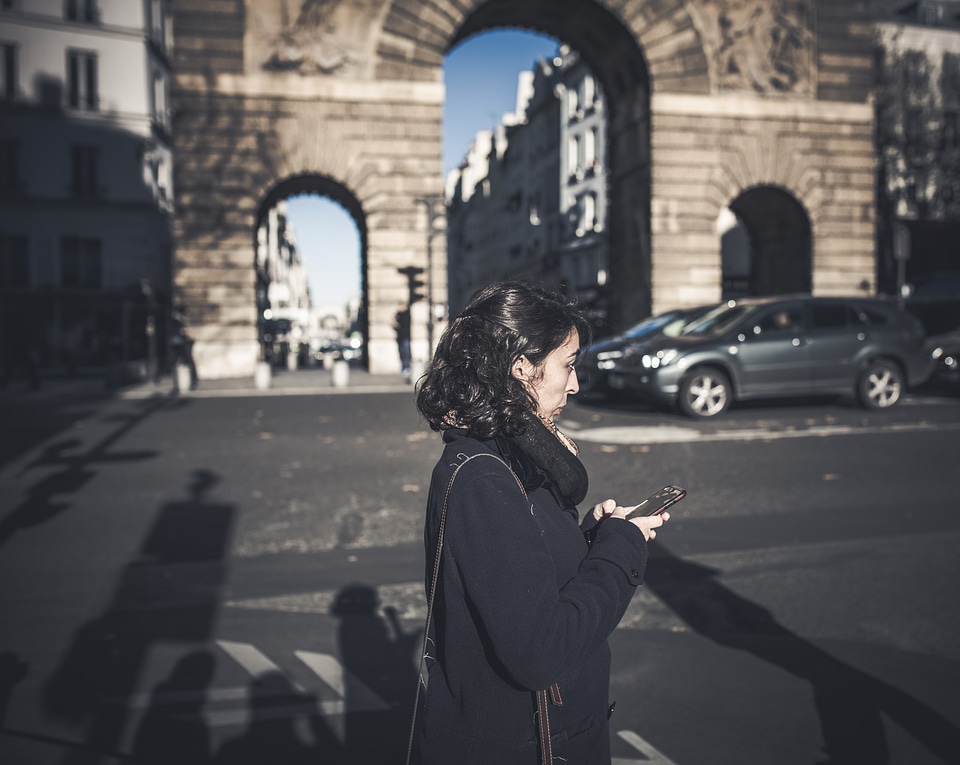 Brunette Walking the Street with a Smartphone in her Hands
