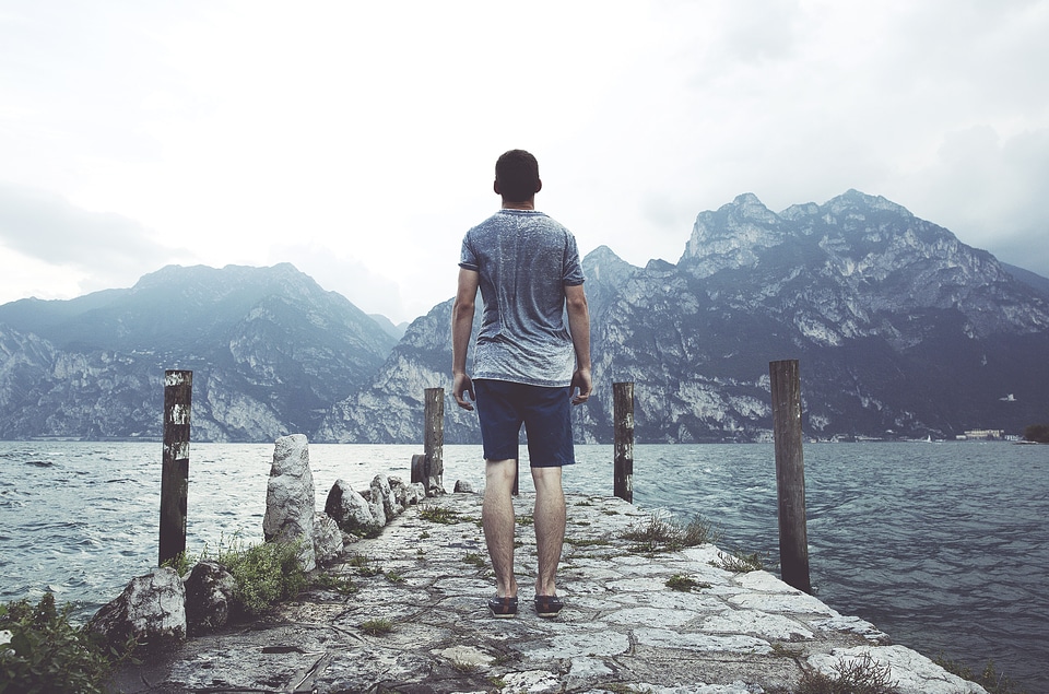 Young Man on a Stone Pier in front of a Mountain Lake photo