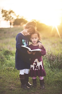 Happy Sisters Hugging with Love and Reading Book Together photo