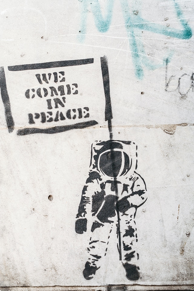 Dirty Wall with Graffiti Astronaut Holding Flag We Came in Peace