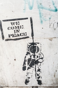 Dirty Wall with Graffiti Astronaut Holding Flag We Came in Peace