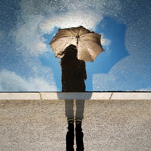 Puddle Reflection Silhouette of Girl with Umbrella against Blue Sky photo