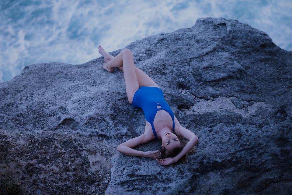 Beautiful Woman in Blue Swimsuit Lying on Rock photo