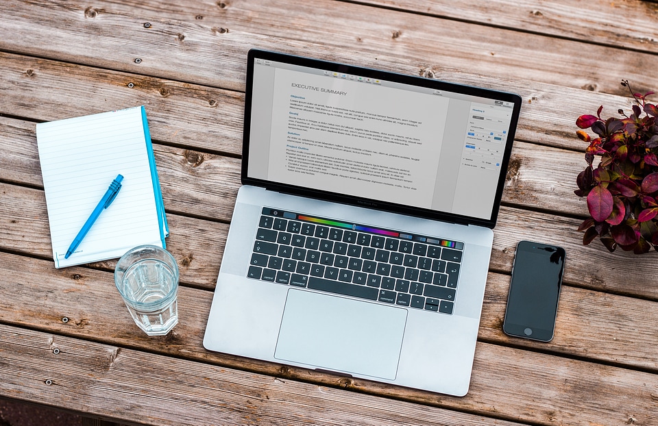 Laptop, Notebook, Flower and iPhone on Brown Wooden Table photo