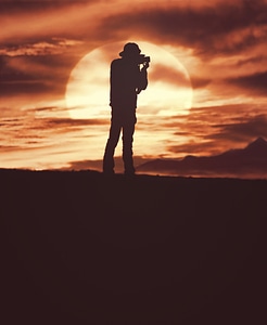 Photographer Silhouette Shooting Outdoors at Sunset Background photo