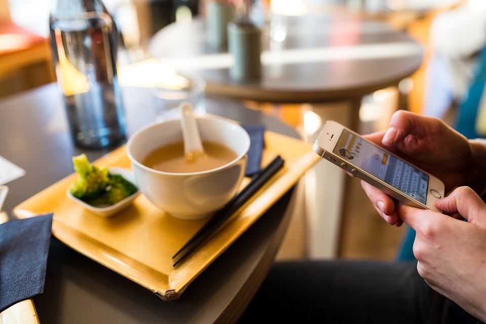 Someones Hands with iPhone in Restaurant