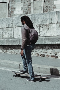 Young Black Man with Dreadlocks Getting on his Skateboard photo