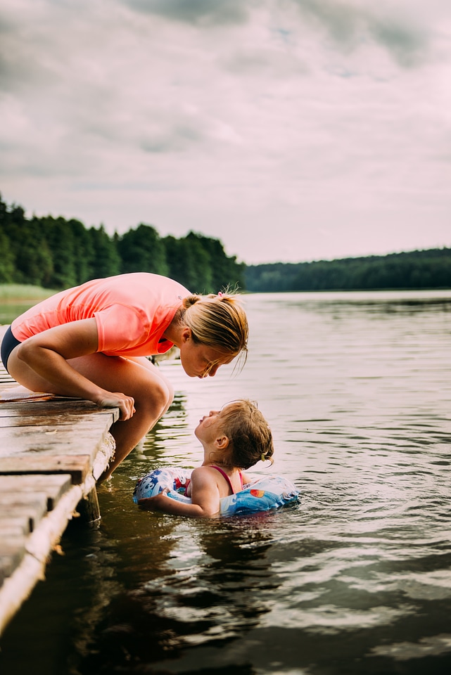Mother Sitting on a Jetty Her Daughter Swim in the Lake