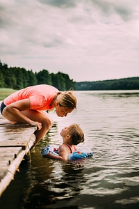 Mother Sitting on a Jetty Her Daughter Swim in the Lake photo