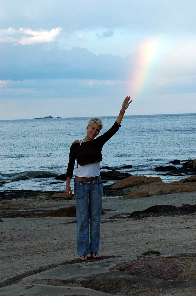 Beautiful woman on seashore against rainbow