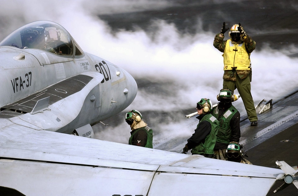 Flight deck Sailors position an F-18 Hornet