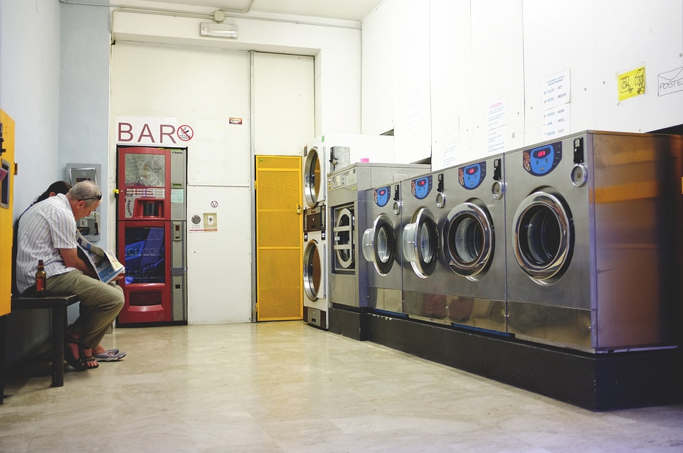 A row of industrial washing machines in a public laundromat