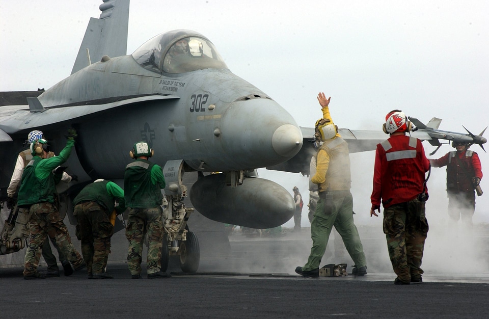 An aircraft director signals the pilot of an F/A-18C