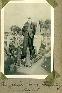 English War Cemetery in Desert. Serviceman standing near a grave. photo