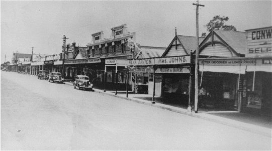 Shops in Barton Street, Kurri Kurri, NSW, [n.d.]. Includes Conway's Cash Stores, Mrs Johns Millinery & Drapery, and Alva Davies' shop. photo