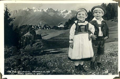 A small girl and boy in national dress standing in an alpine meadow in the Val Pusteria above Maria Sares, Brunico, Italy, [1944] - Postcard,