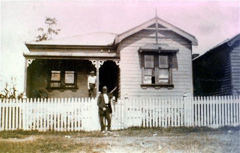 Two gentlemen in front of a house, one on the verandah, the other outside the fence, [n.d.] photo