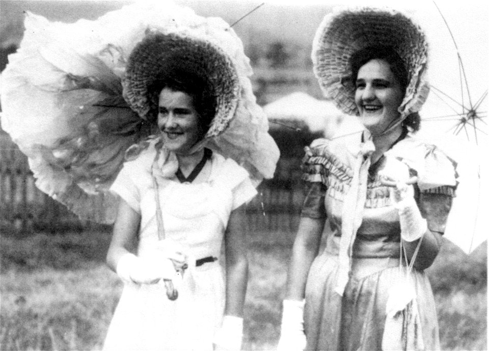 Janice McDonald (right) and a friend in bonnets, carrying parasols at the Mulbring School Centenary, 12 November 1949,