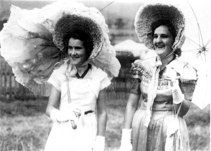 Janice McDonald (right) and a friend in bonnets, carrying parasols at the Mulbring School Centenary, 12 November 1949, photo
