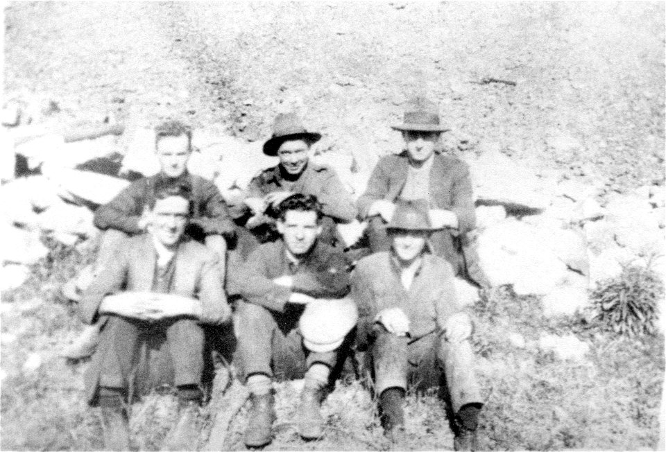 Six gentlemen seated on the ground outdoors, [n.d.]