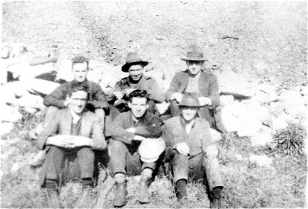 Six gentlemen seated on the ground outdoors, [n.d.] photo