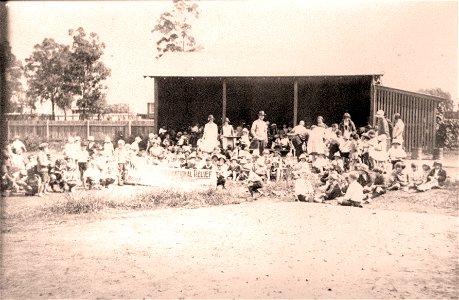 Crowd near the shelter shed of Kurri Kurri Superior Public School with a banner "[Workers'] International Relief, [n.d.0